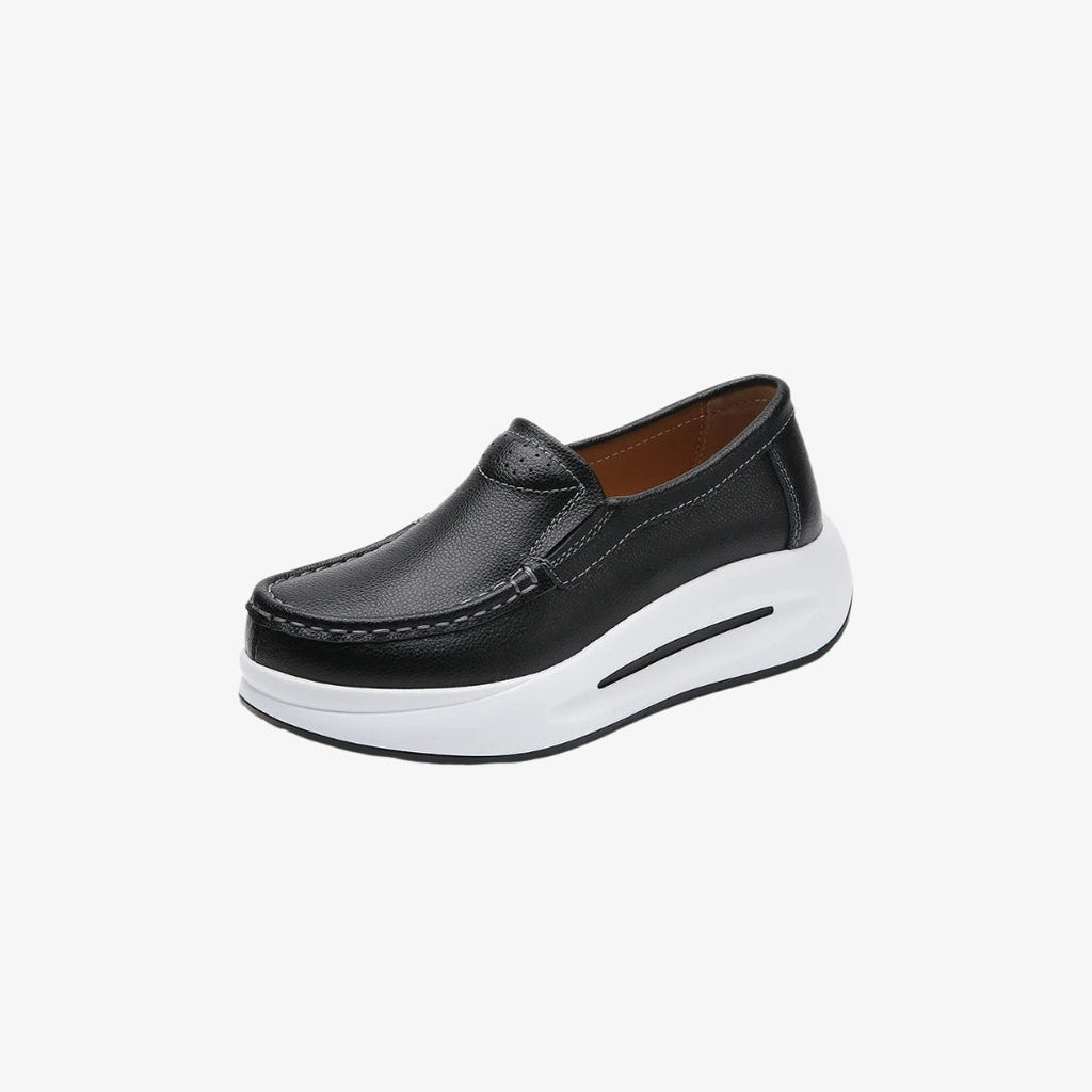 Mocasines para mujer en piel sintética negra con una gruesa suela blanca para un estilo moderno y cómodo. Su diseño minimalista incluye costuras visibles y un ajuste fácil, perfectos para un look elegante y desenfadado.