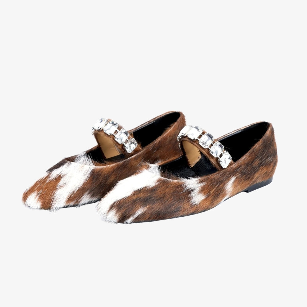 Mocasín bailarina de piel de ternera para mujer, con estampado de vaca y correa de strass, sobre fondo gris