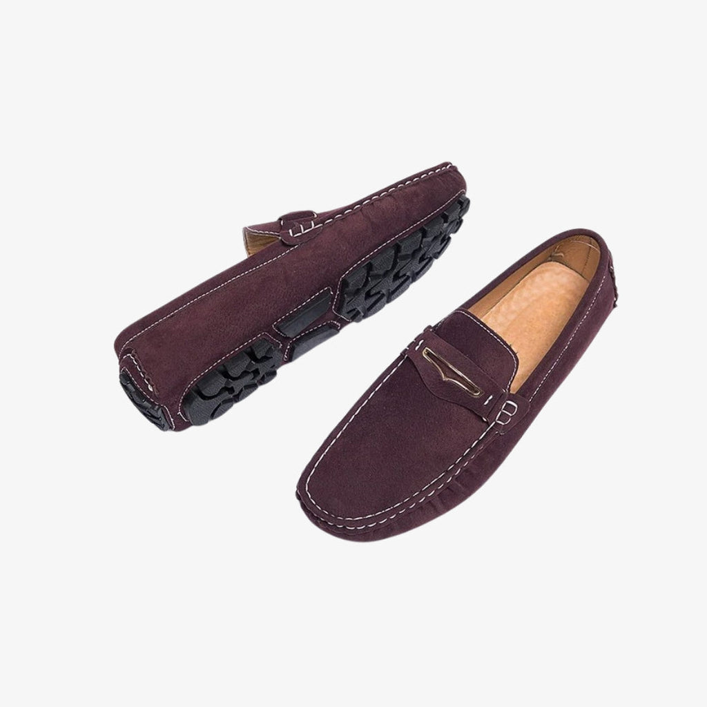 Mocasines cómodos de ante para hombre en color burdeos. Estos elegantes zapatos tienen costuras en contraste blancas, una hebilla metálica discreta en la parte superior y una suela dentada negra para un mejor agarre. El interior acolchado aporta una comodidad óptima a diario.
