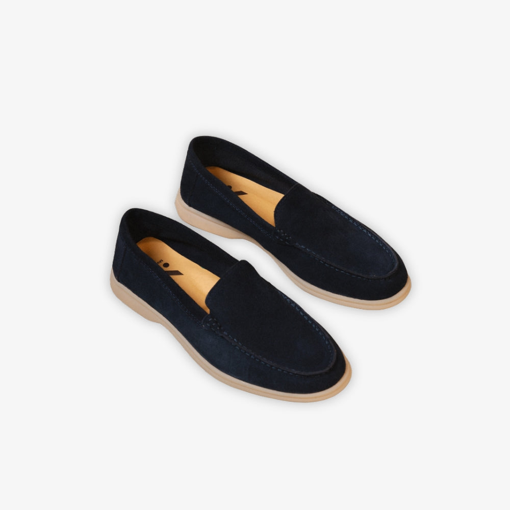 Mocasín náutico azul colocado en el suelo sobre un fondo beige