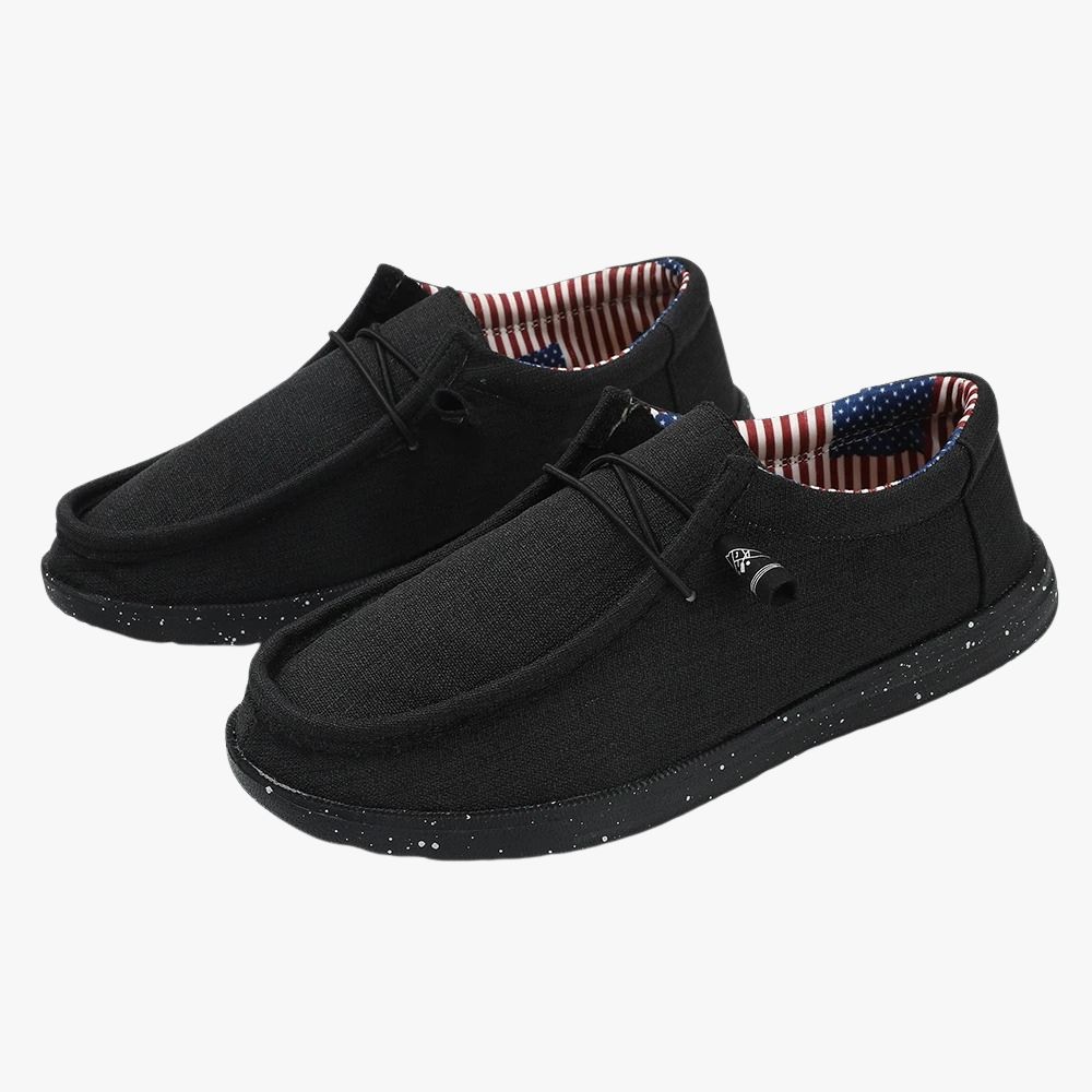 Mocasines negros de tejido con suela gruesa. El interior de tejido tiene un estampado con la bandera estadounidense.