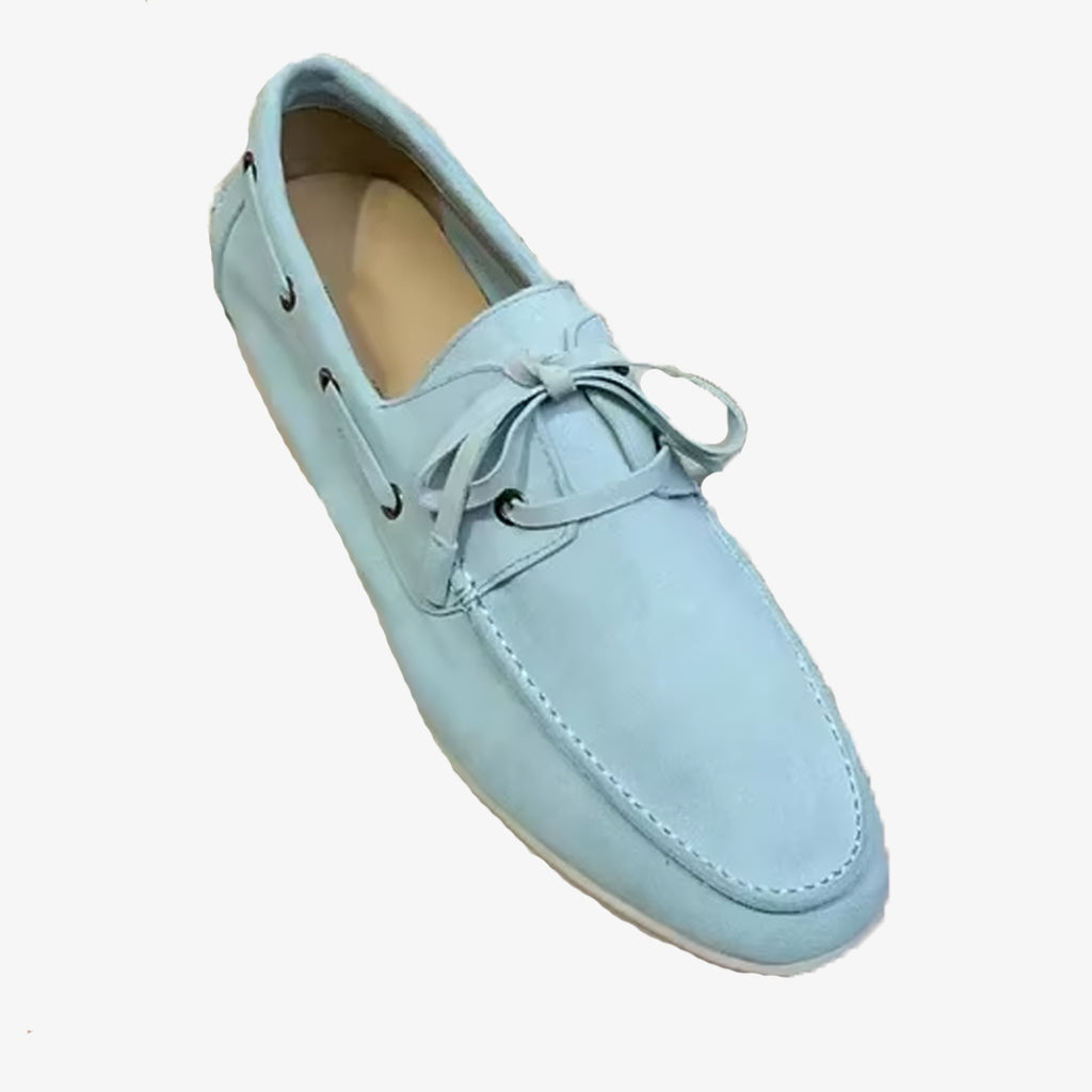 Un mocasín náutico de ante elegante azul claro sobre fondo blanco