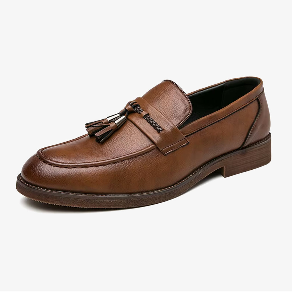 Un mocasín elegante de cuero marrón con borla para hombre sobre fondo blanco