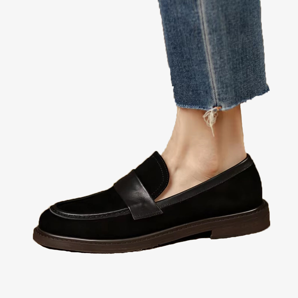 Un mocasín clásico de mujer de ante negro con correa, llevado con vaqueros