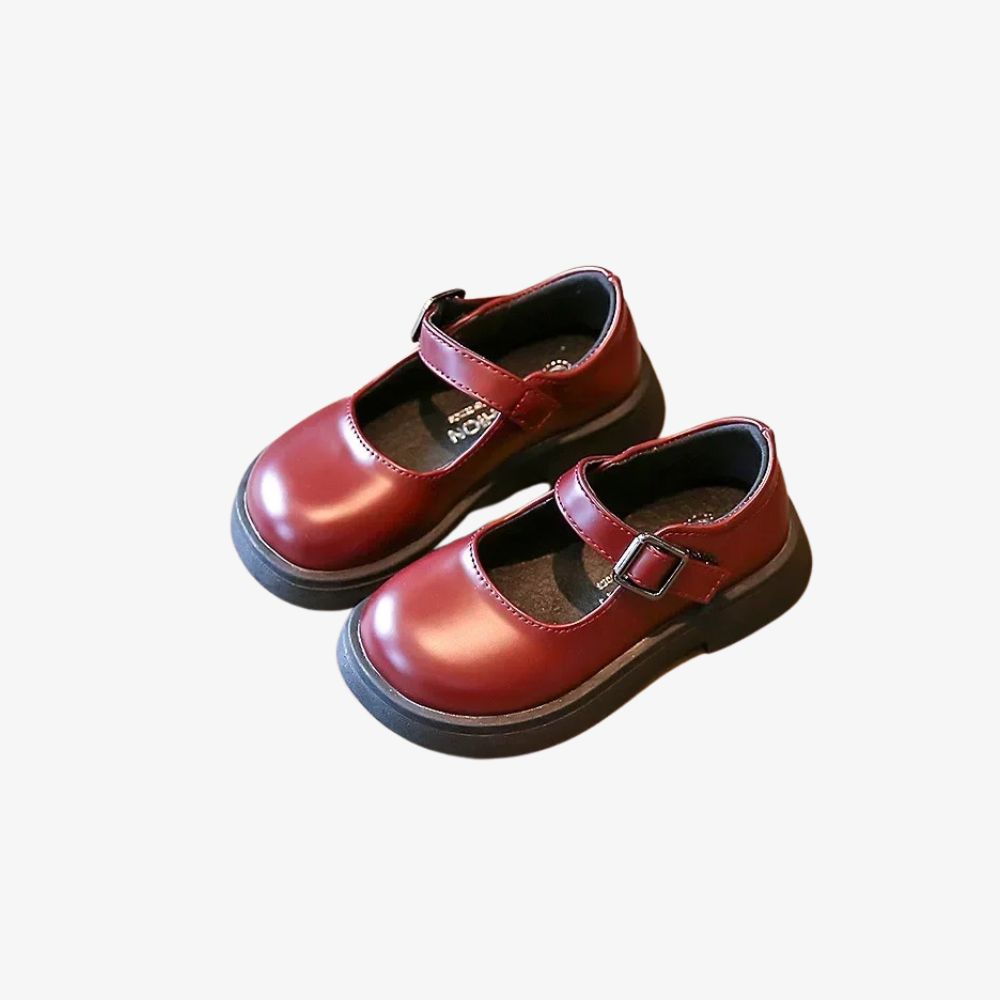 Par de mocasines burdeos de niño, con una correa.