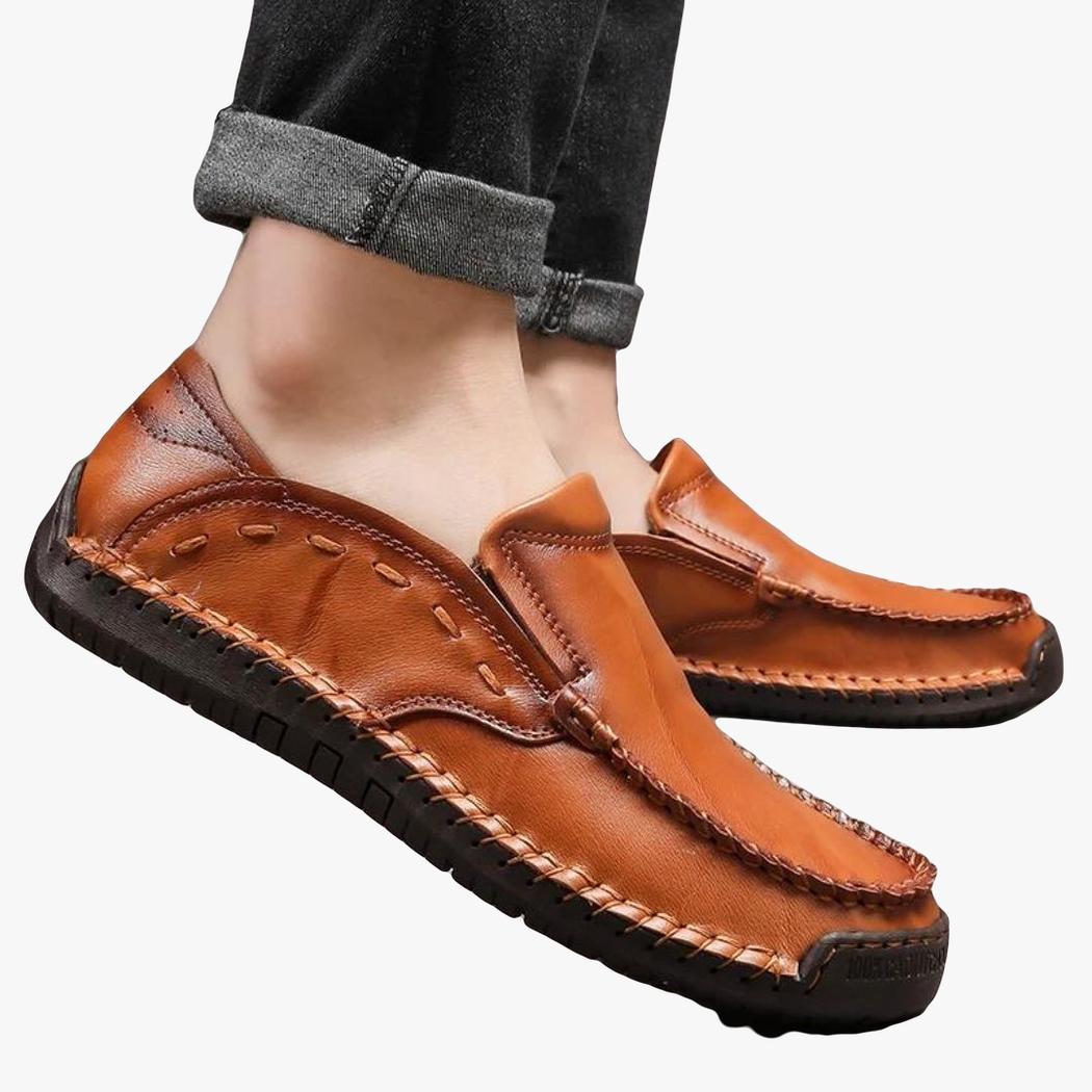 Se ven los pies de un hombre con unos mocasines flexibles de piel sintética de color camel