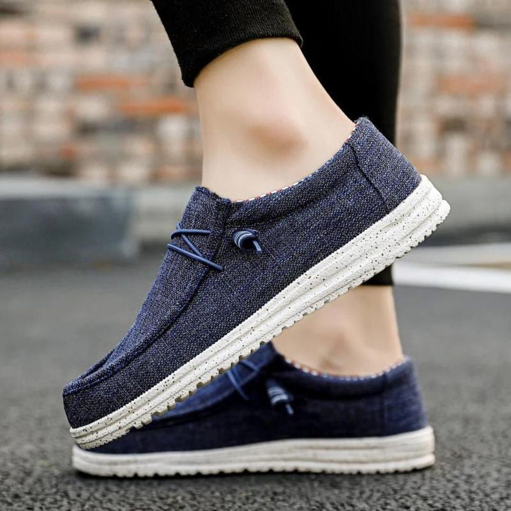 Se ve a un hombre con unos mocasines azules desenfadados, solo se le ven los pies