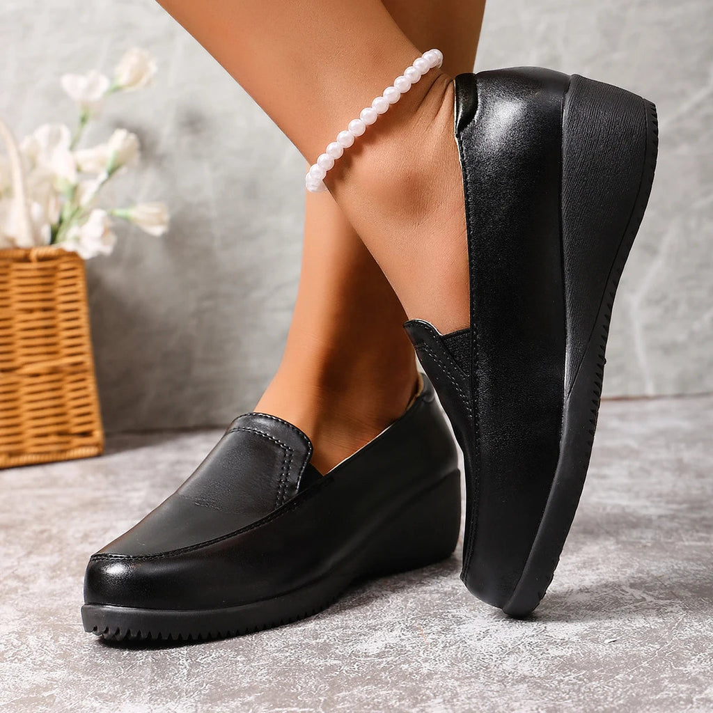 Mocasín negro de cuña para mujer, puesto en el pie