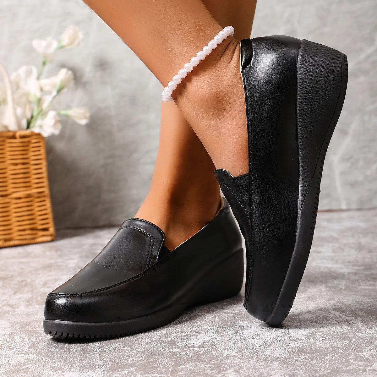 Mocasín negro de cuña para mujer, puesto en el pie