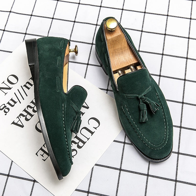 Par de mocasines verdes con borlas sobre una superficie de cuadros blancos