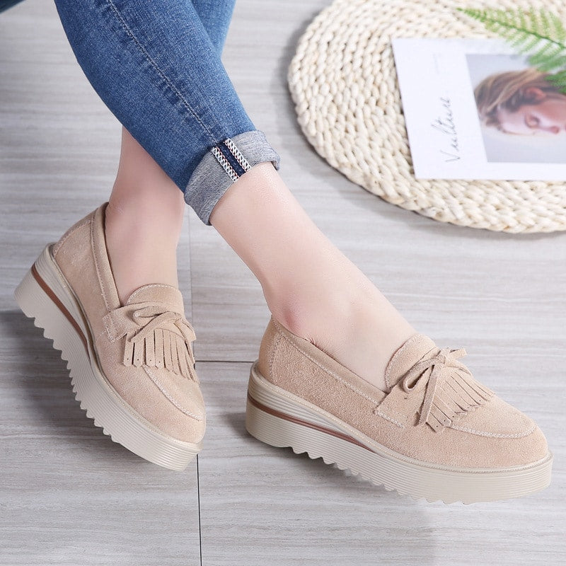 mocasín de cuña con borlas beige que lleva una mujer