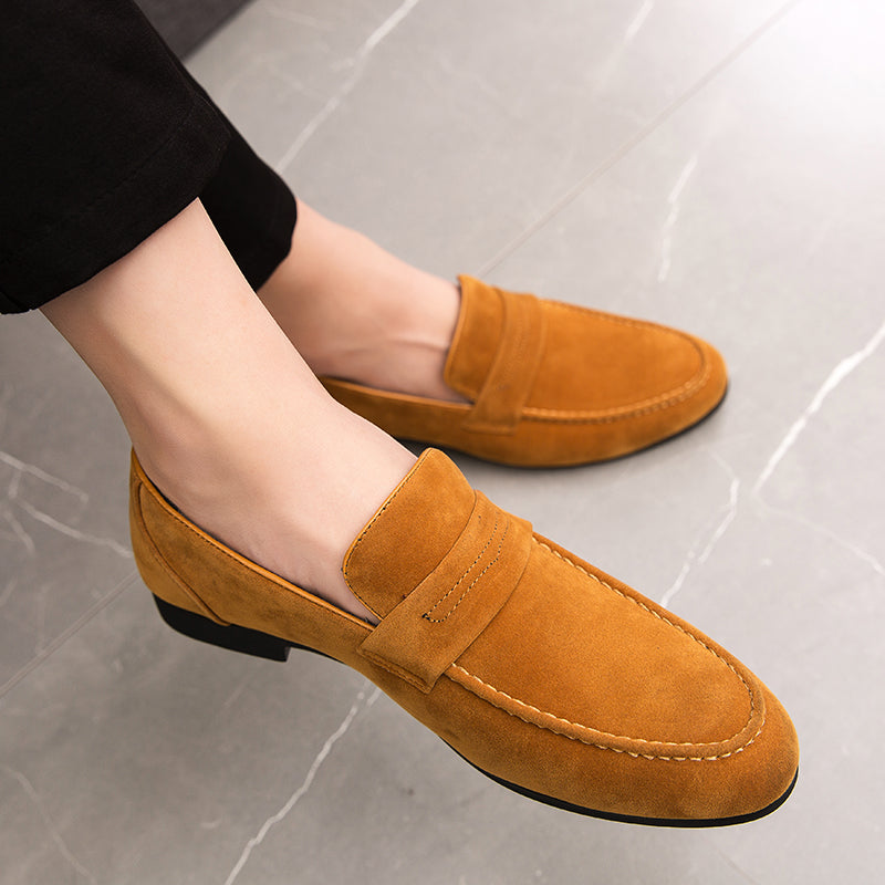 mocasines marrones usados por un hombre con las piernas cruzadas y pantalones negros