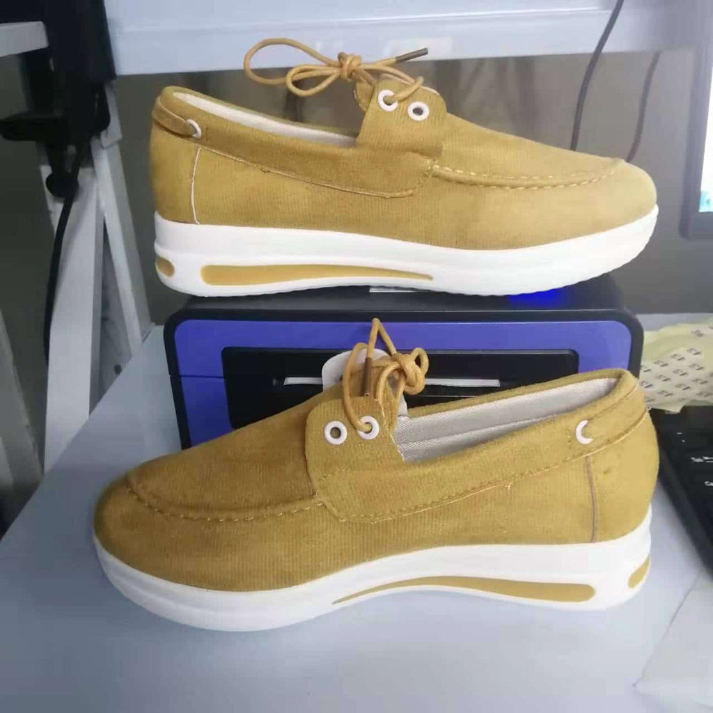 Mocasines amarillos con tacón blanco delante de una caja.