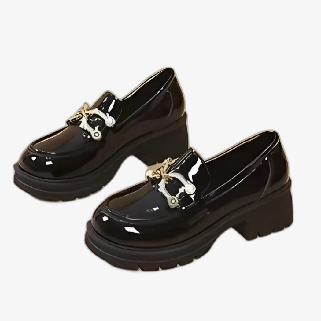 Mocasines de charol negro para mujer, de estilo chic y moderno. Con tacones gruesos que aportan presencia y buena estabilidad, están adornados con una elegante hebilla metálica plateada en el empeine, que añade un toque refinado a su diseño brillante.