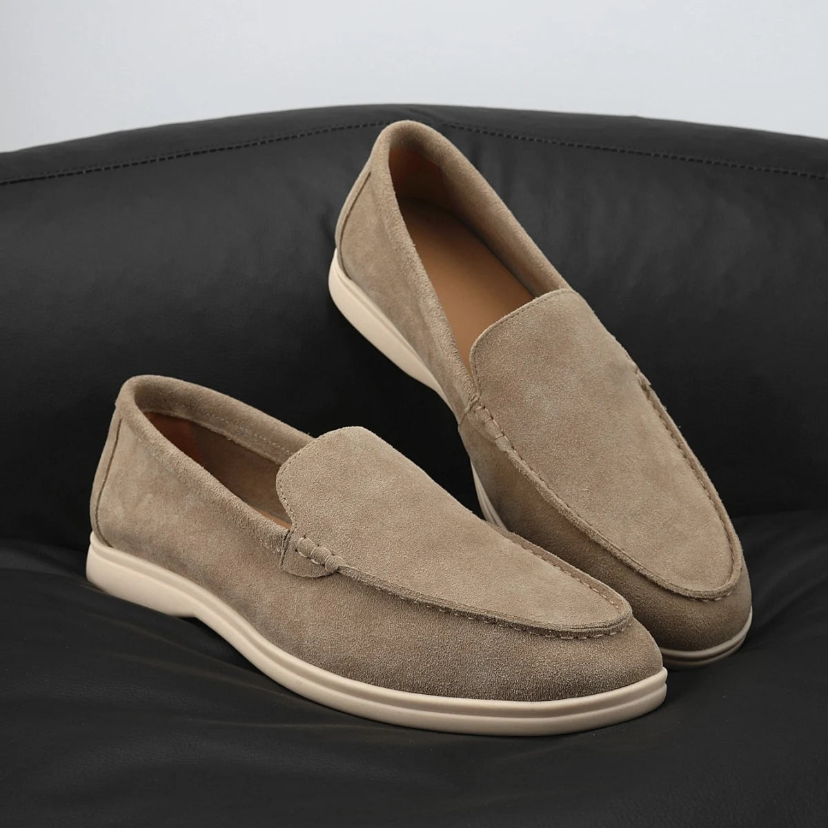 Mocasines flexibles de hombre en ante taupe con suela clara, color camel, detalle de las costuras