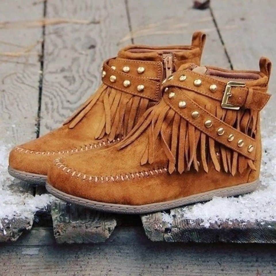 Mocasines indios con flecos y hebillas en ante color camello sobre tablones de madera
