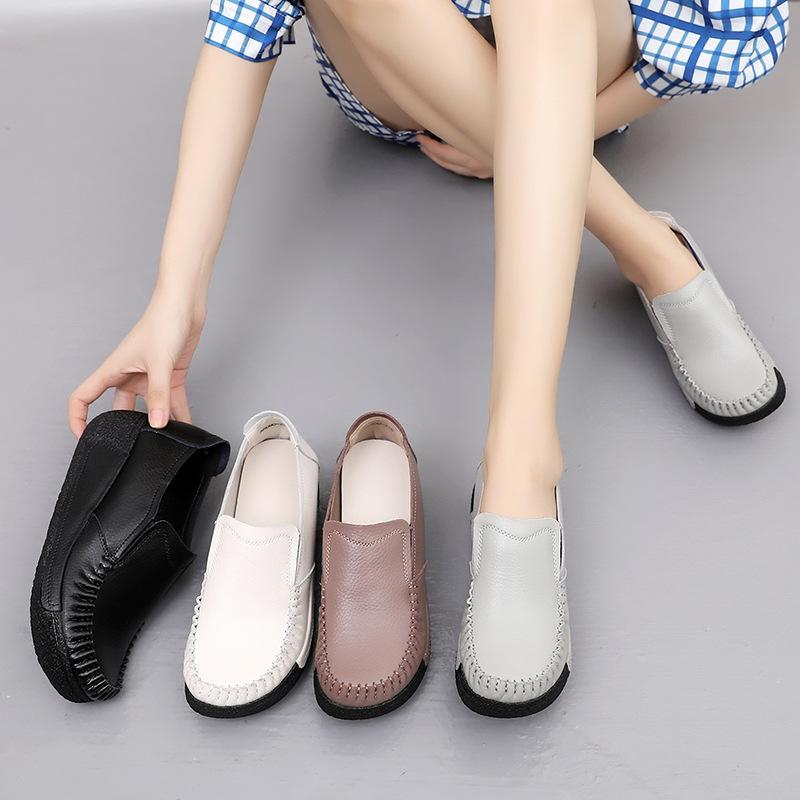 Pierna de mujer con zapatos grises en los pies y otros zapatos a su lado, negros, blancos y marrones