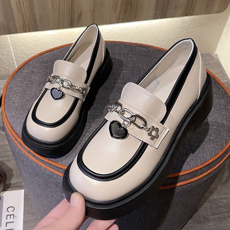 Foto de un par de mocasines blancos de plataforma sobre un taburete gris