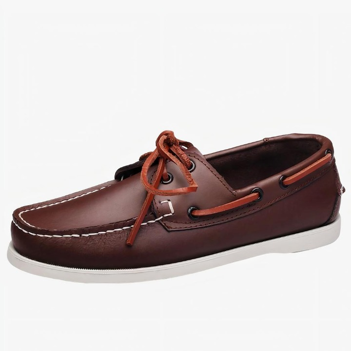 Un mocasín náutico de piel marrón con cordones sobre fondo blanco