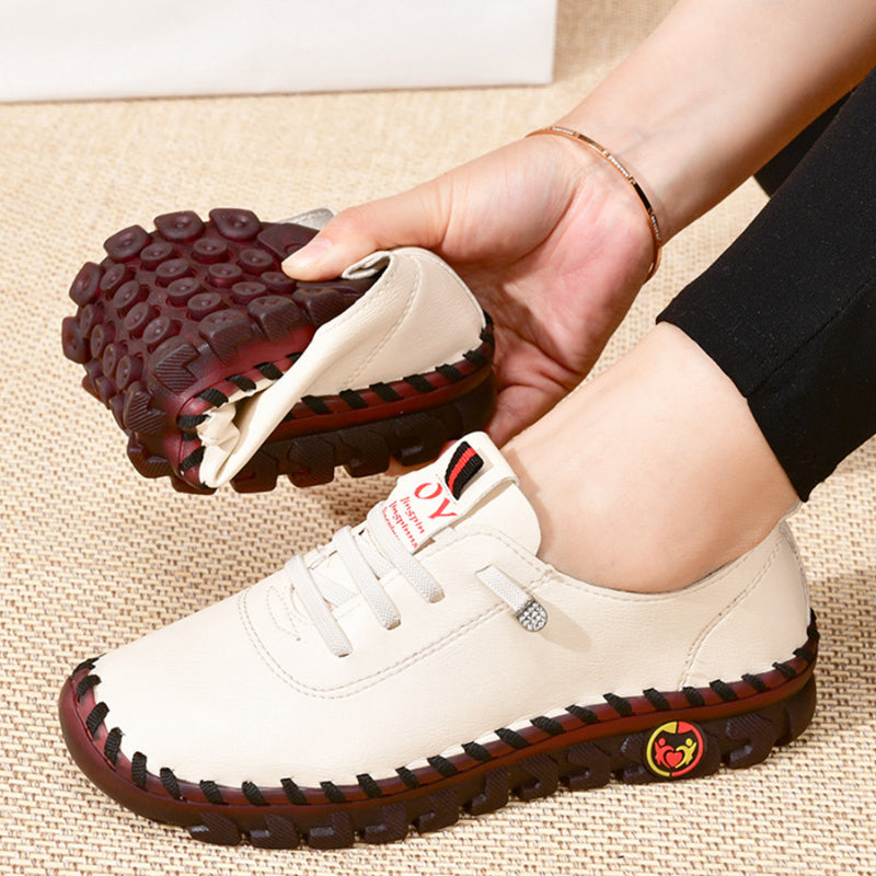 Pie izquierdo de mujer con un mocasín ortopédico blanco, con el segundo zapato doblado en la mano derecha