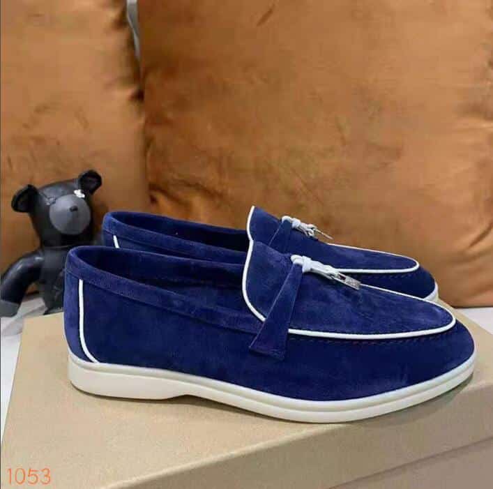 Mocasín en ante azul con ribetes blancos y una borla dura en la parte delantera del zapato que se coloca sobre una caja de zapatos