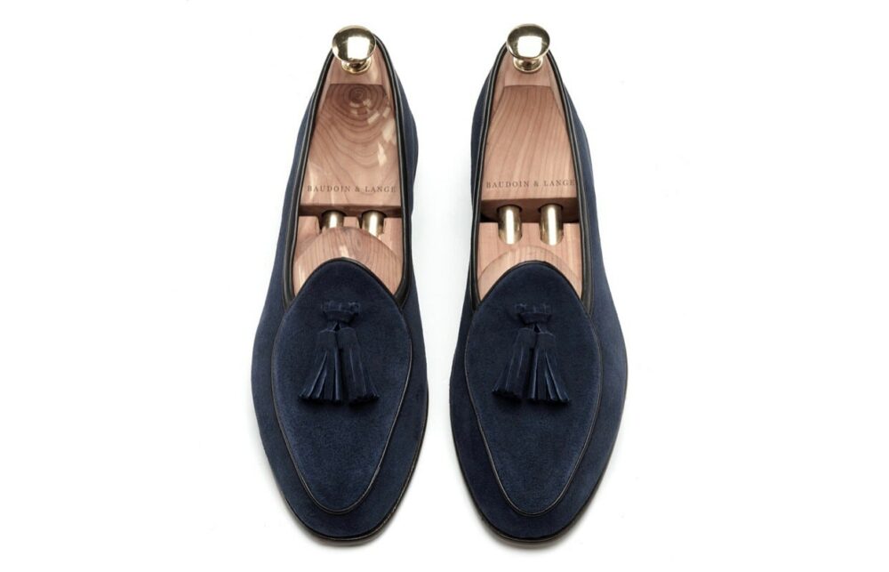 Par de mocasines de ante azul marino sobre fondo blanco