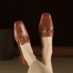 mocasín de cuero marrón con un anillo en la parte superior usado por una mujer