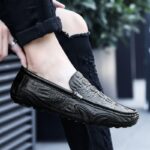 Foto de un mocasín de cuero negro llevado por una mujer con pantalones negros en una calle