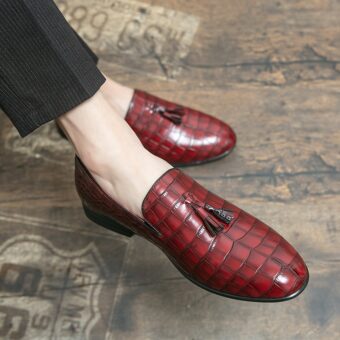 Pies calzados con mocasines rojos efecto cocodrilo con una borla en la parte superior del zapato