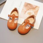 mocasín de niña de piel sintética marrón sobre un periódico