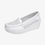 Mocasín blanco de perfil, con suela de cuña y perforaciones en la parte delantera y los laterales.
