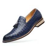 Mocasín de cuero trenzado azul con suela de color claro y borlas decorativas sobre fondo blanco.