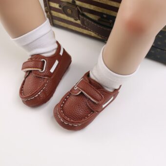 Bebé con calcetines blancos y mocasines marrones tipo barco