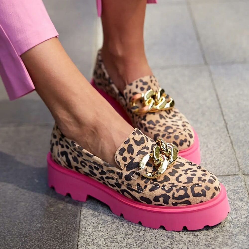 Pie de mujer con pantalón rosa y mocasines de leopardo con suela rosa