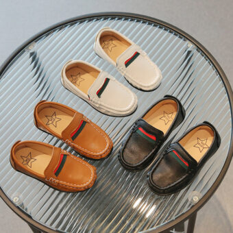 Mocasines suaves en efecto cuero con un diseño rojo y verde para chicos con fondo de mesa de cristal