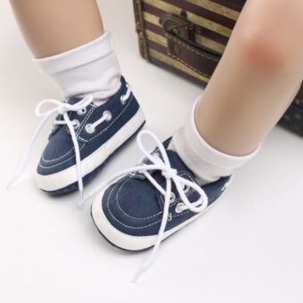 Piernas de bebé con calcetines blancos y mocasines azules estilo barco