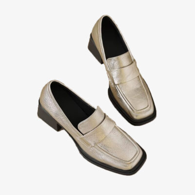 Mocasines dorados con tacón para mujer sobre fondo blanco