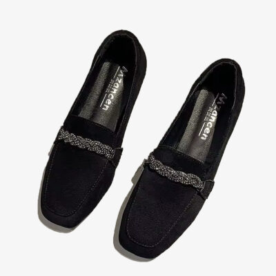 Par de mocasines de ante negro con cadena de brillantes sobre fondo blanco