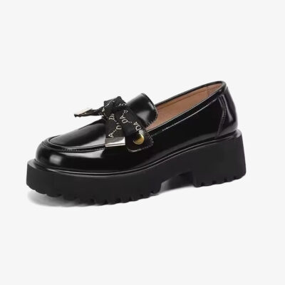 Foto de un mocasín negro de plataforma con lazo sobre fondo blanco